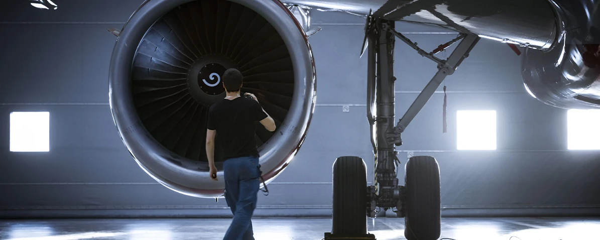 Ein Mann mit Werkzeug vor einer Flugzeugturbine.